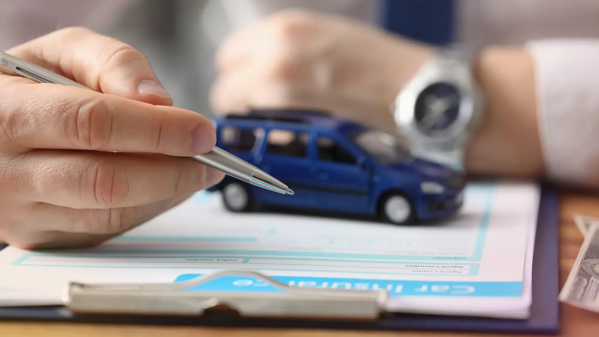 A friendly local insurance agent consults with a driver about auto policy options in their office.
